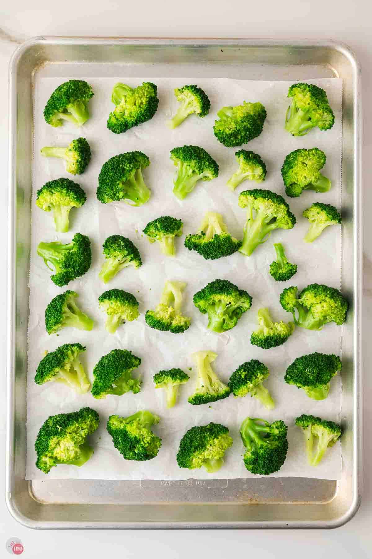 individual broccoli florets on a baking sheet with parchment paper