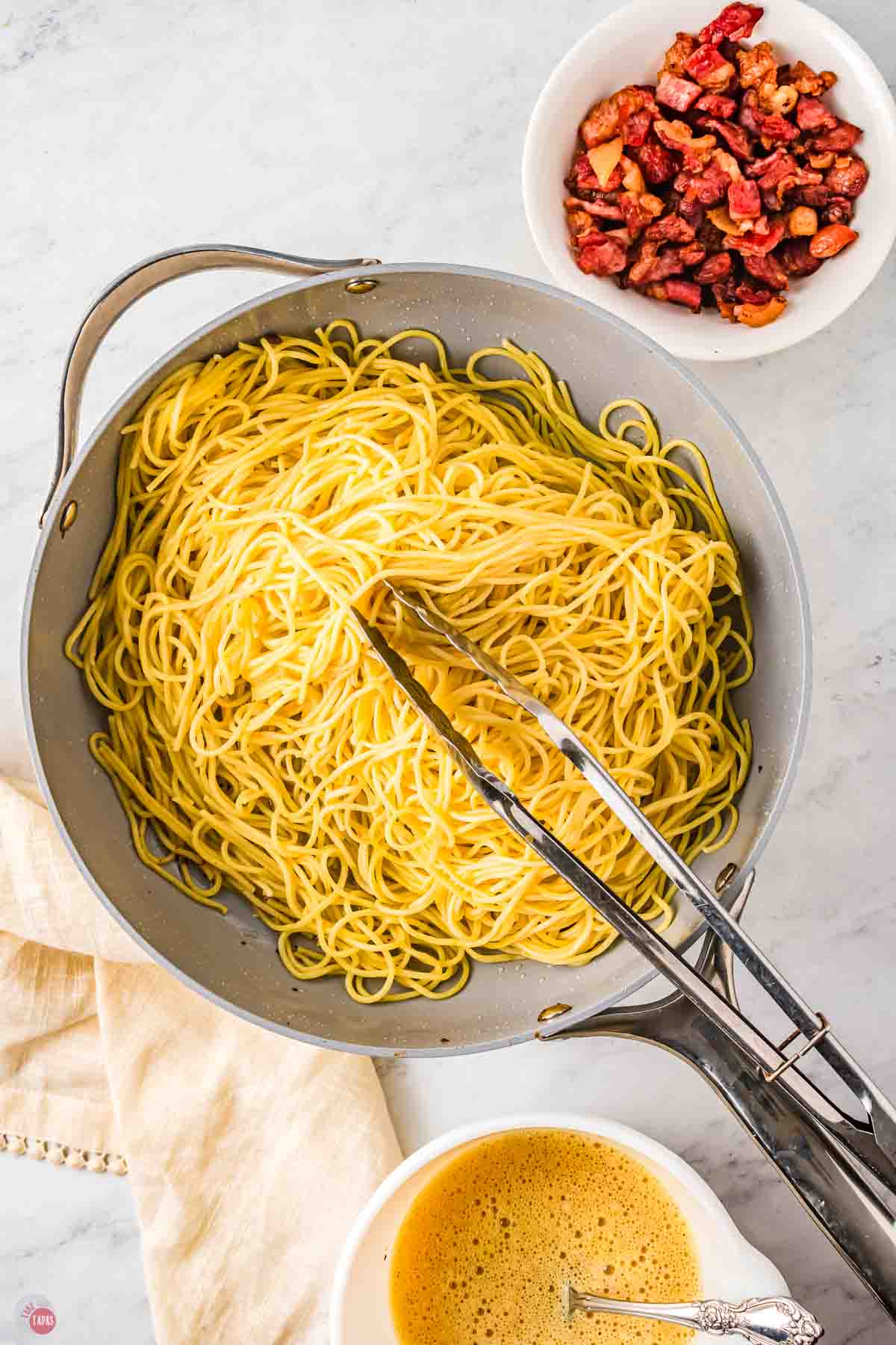 spaghetti noodles being stirred in a pan