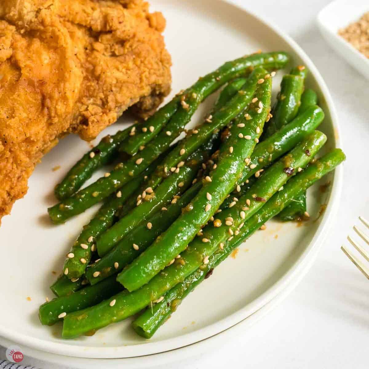 PF Changs spicy garlic green beans on a white plate with fried chicken