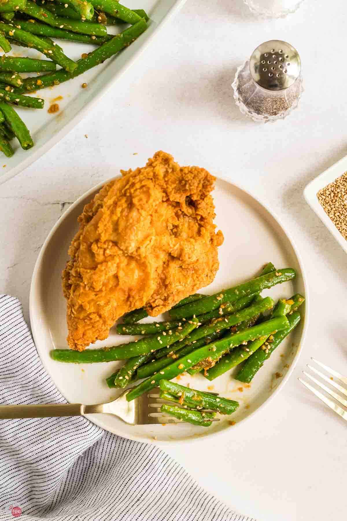 plate of fried chicken and green beans with a fork