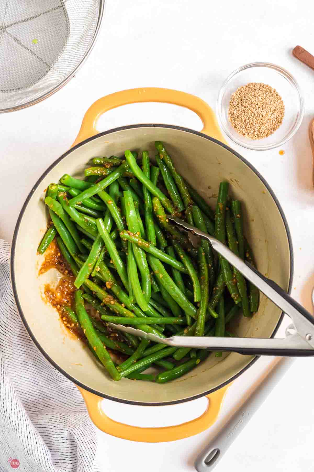tongs stirring green beans in a large pot