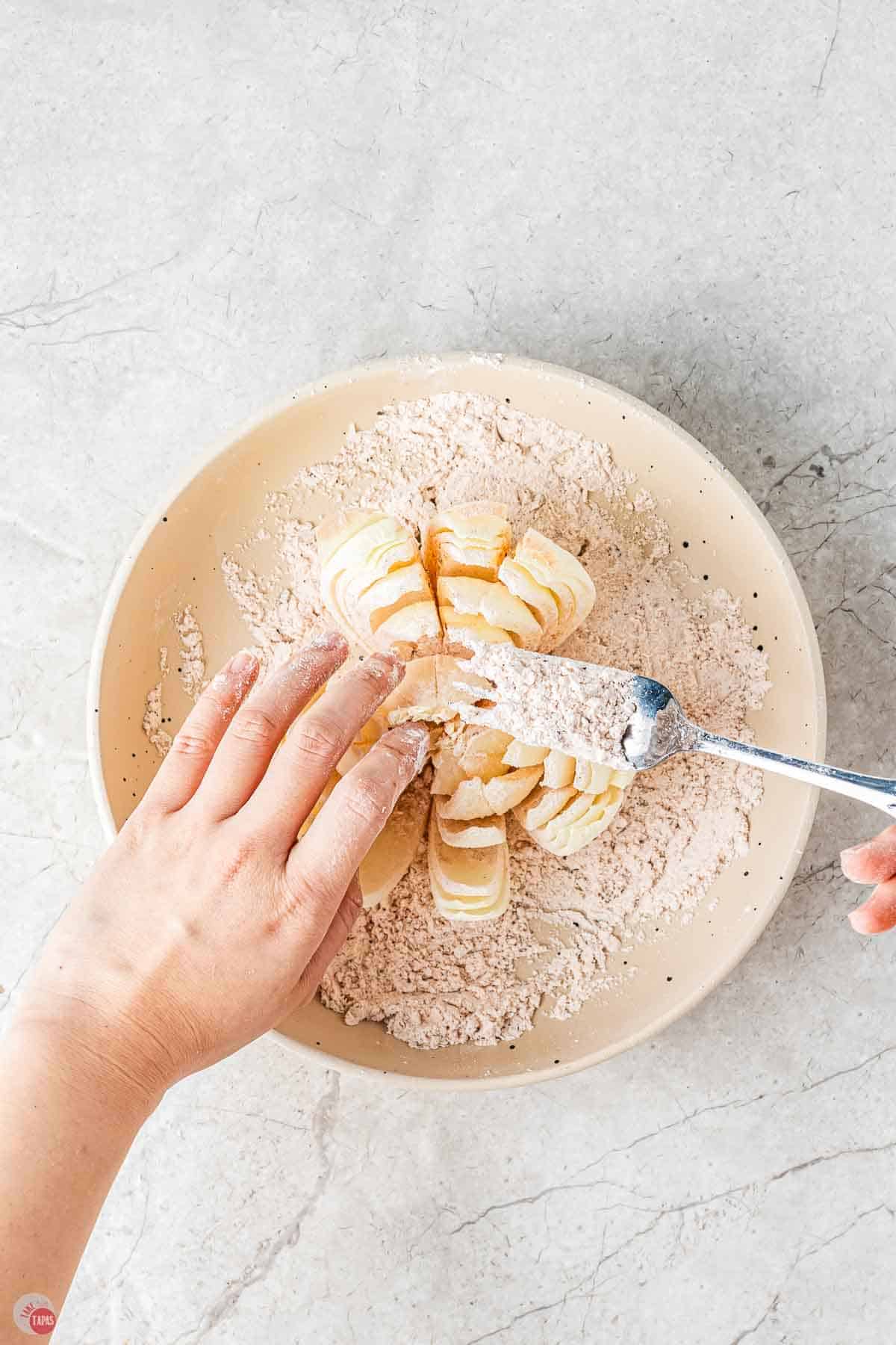 a cut onion on a plate with a fork sprinkling flour over the top of it