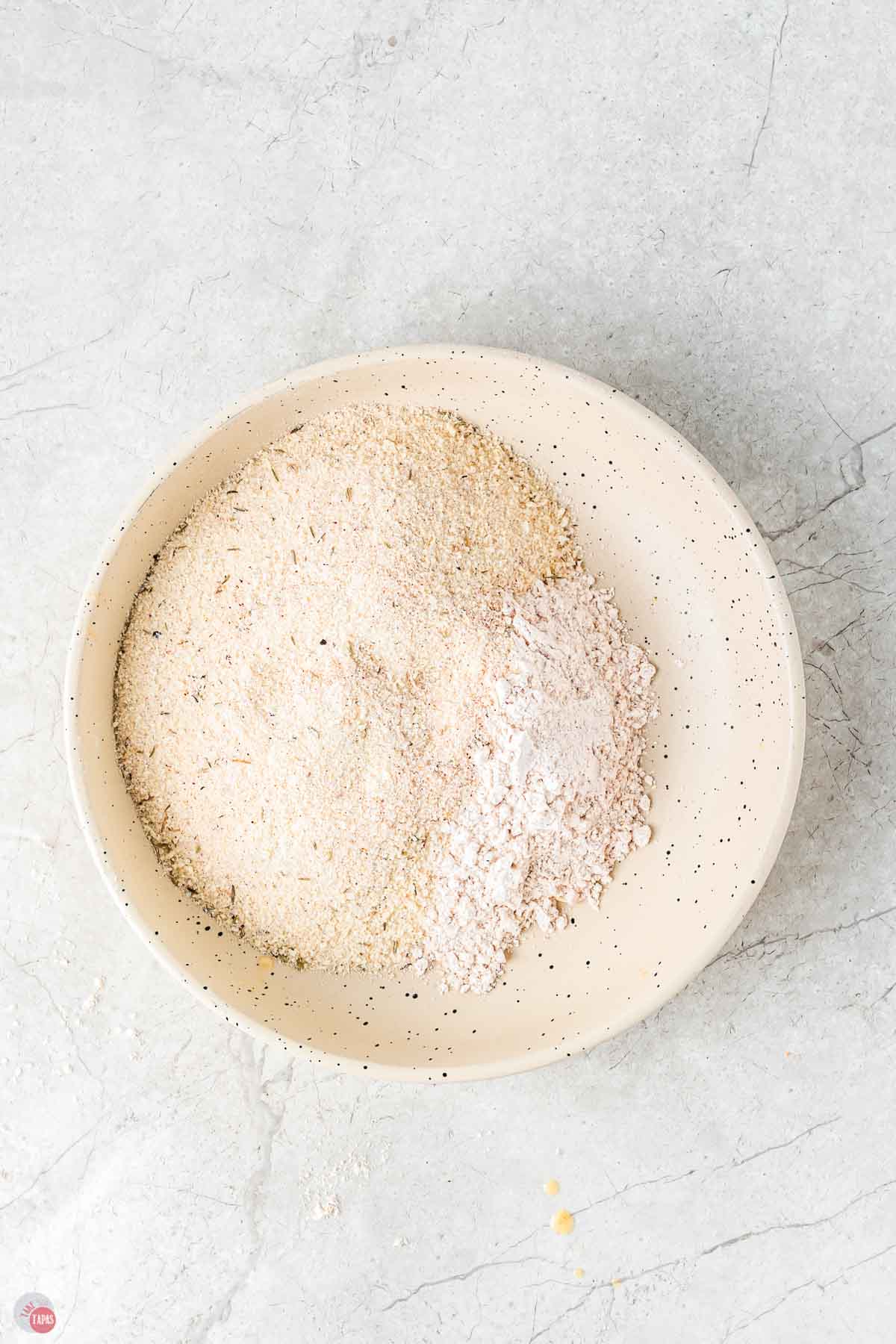 seasoned coating being mixed with flour in a shallow bowl