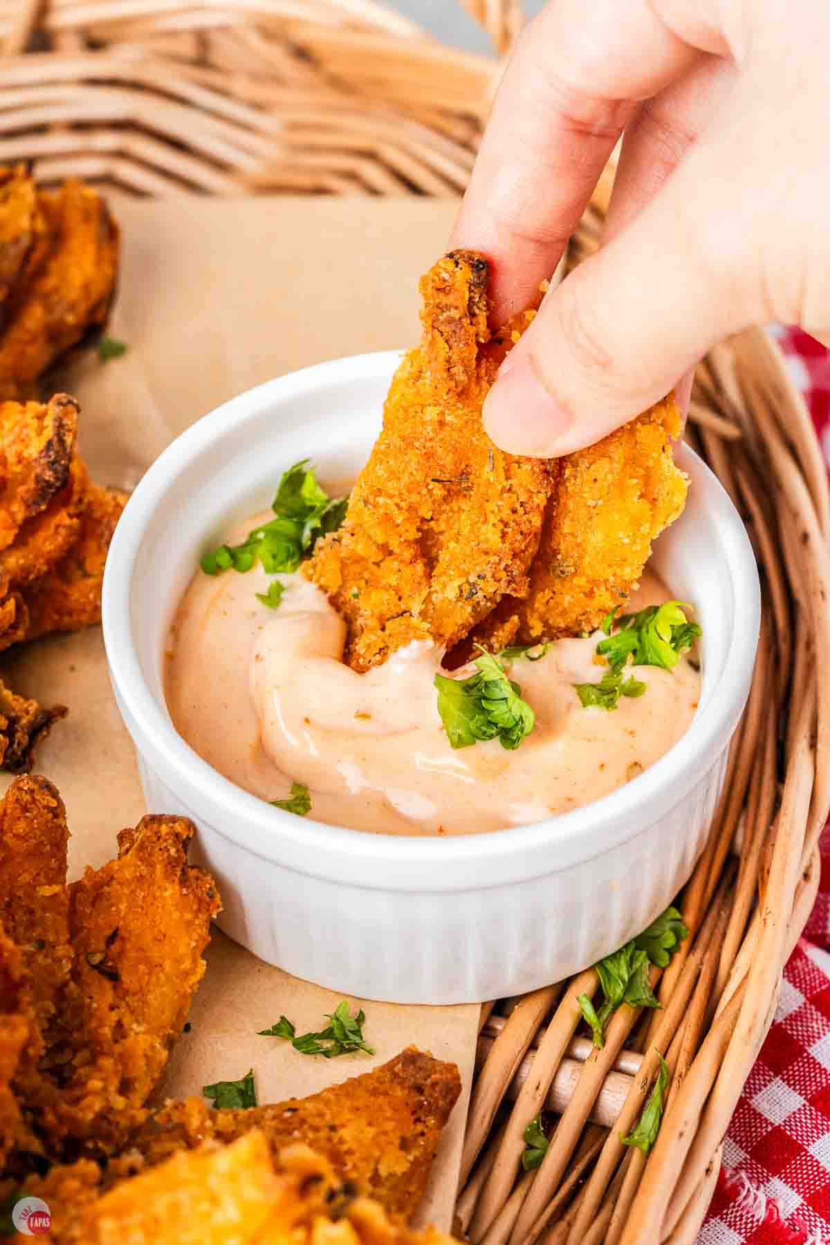 hand dipping fried onion petals in dipping sauce