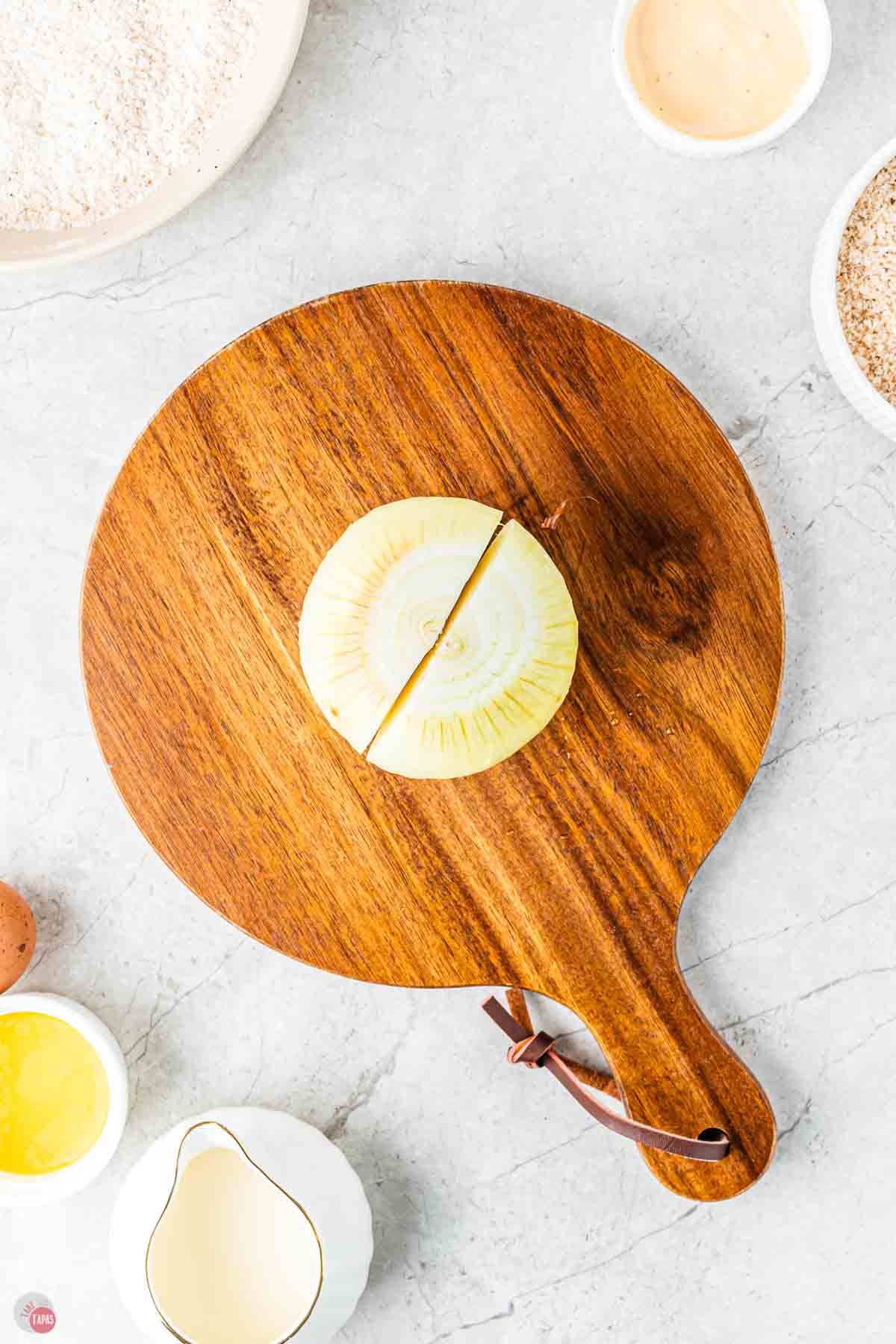 onion on a round cutting board with a cut down the middle