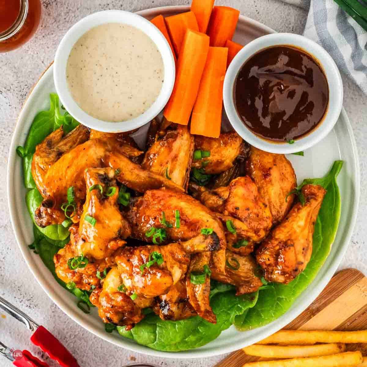 plate of chicken wings with bowl of ranch dressing and carrot sticks