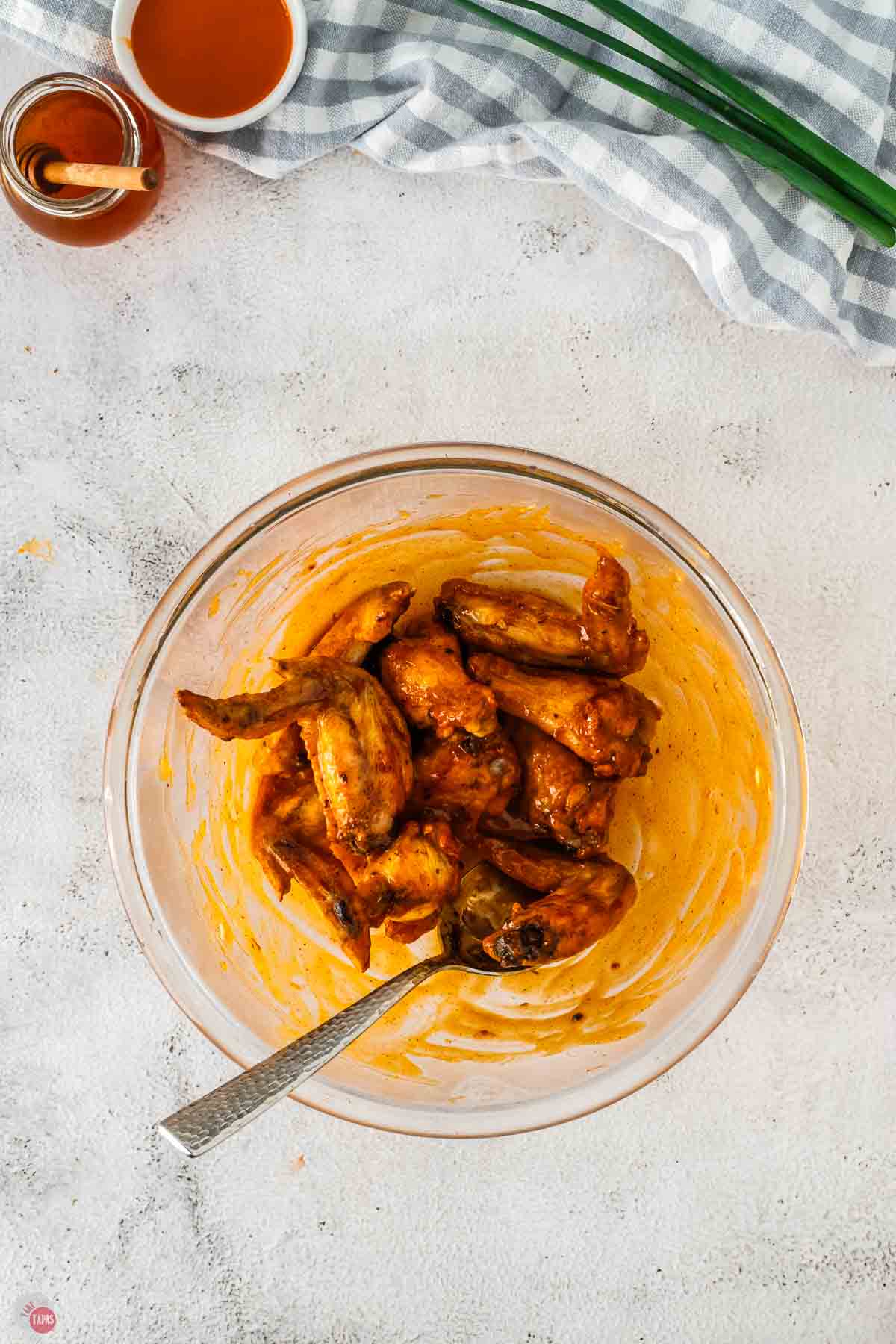 cooked chicken wings in a bowl of buffalo sauce