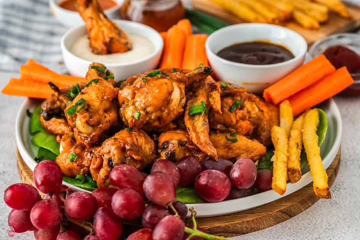 platter of chicken wings with grapes and carrot sticks