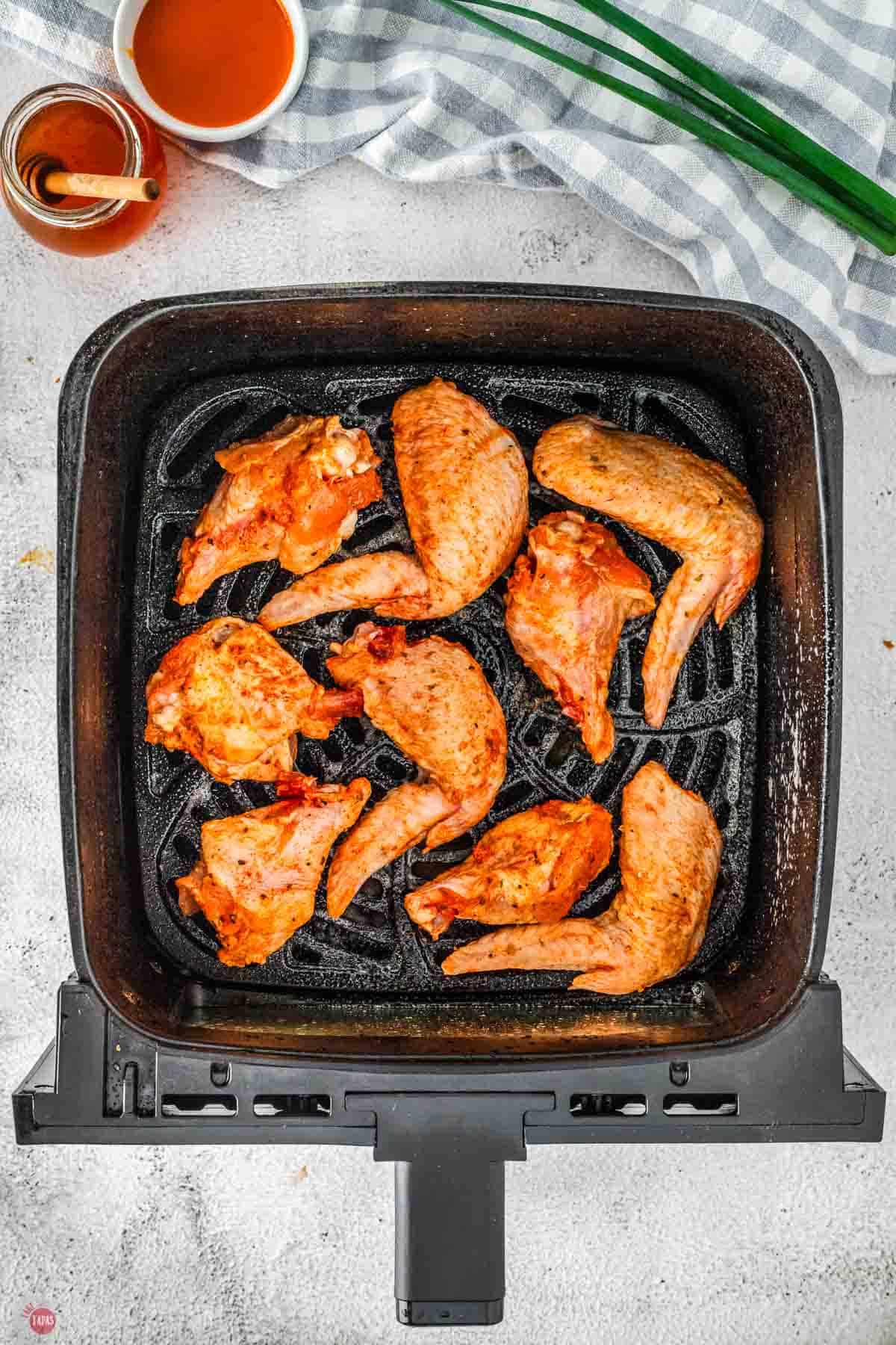 uncooked chicken wings in an air fryer basket