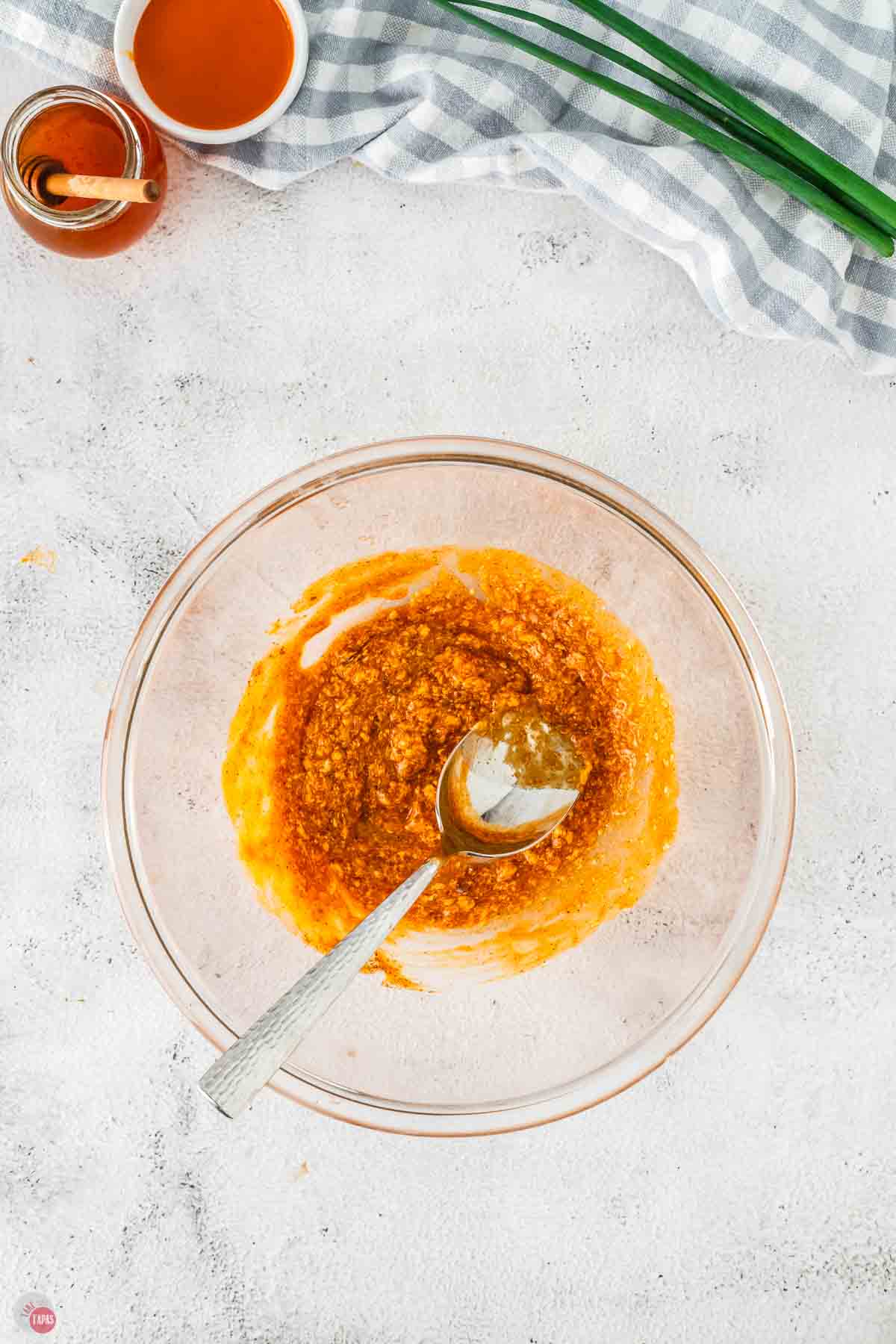 clear bowl with buffalo sauces and spices being mixed with a spoon