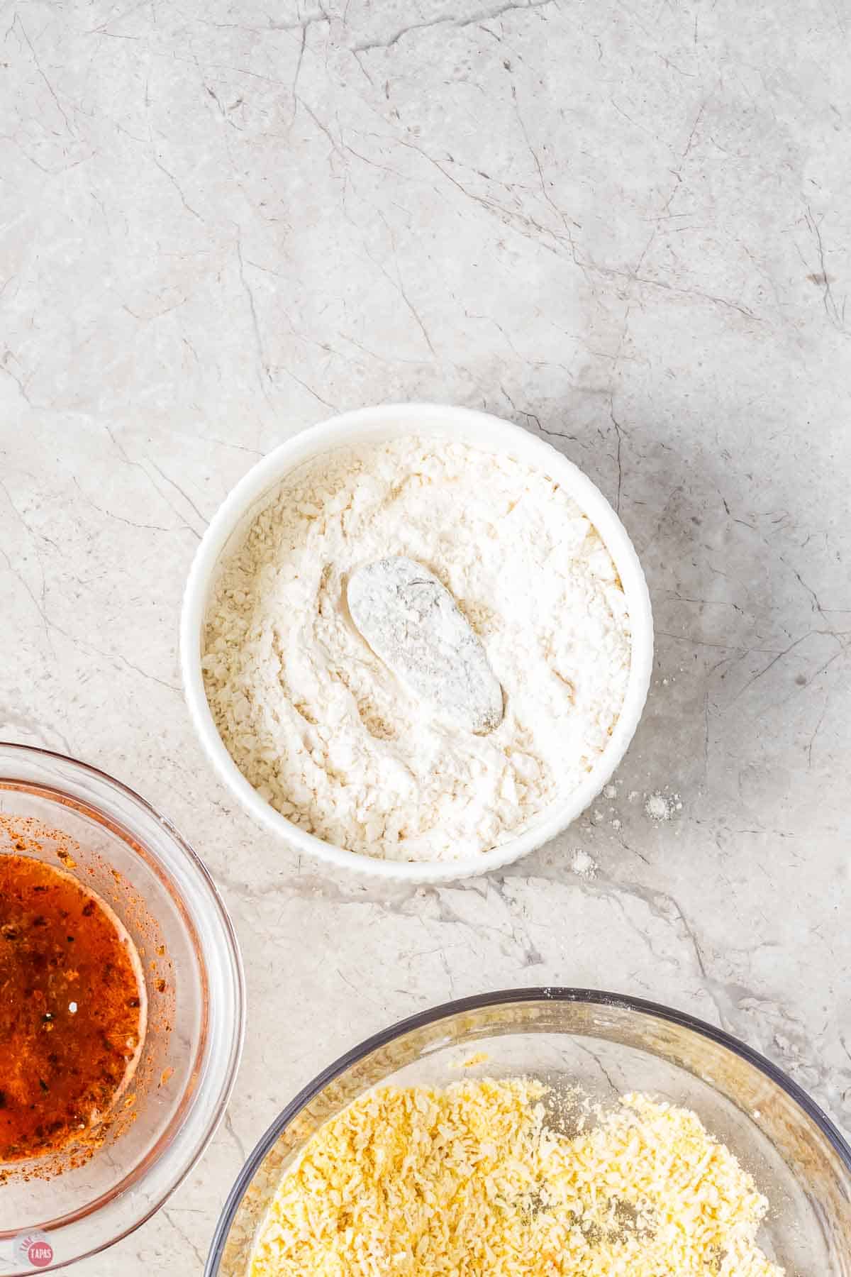 small bowl of flour with a pickle in it