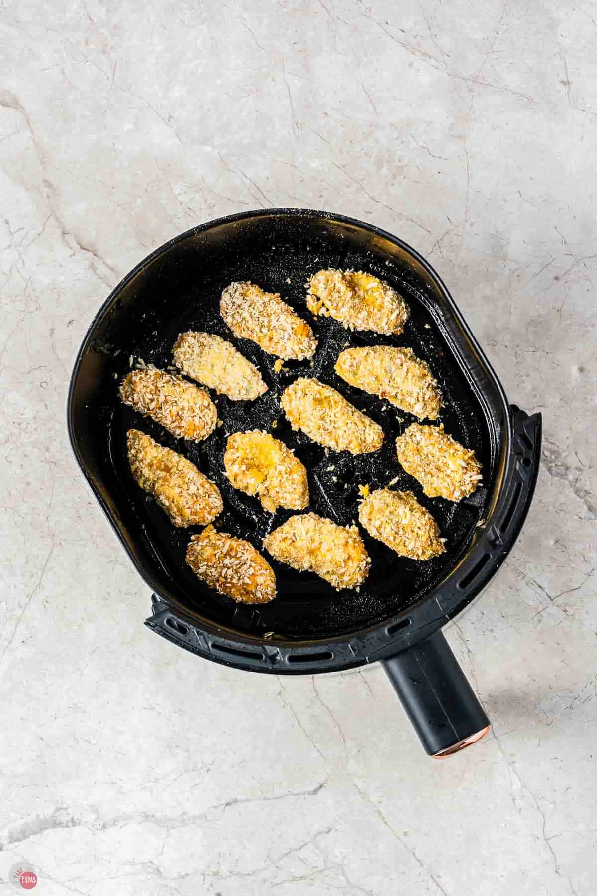 breaded pickle slices in an air fryer basket