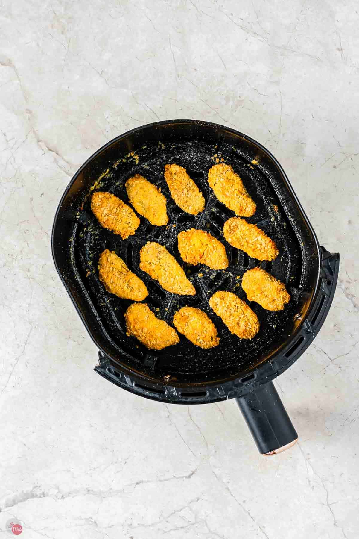 air fryer basket with fried pickles in it