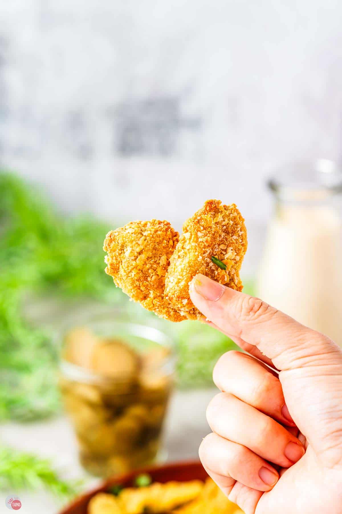 hand holding two fried pickles