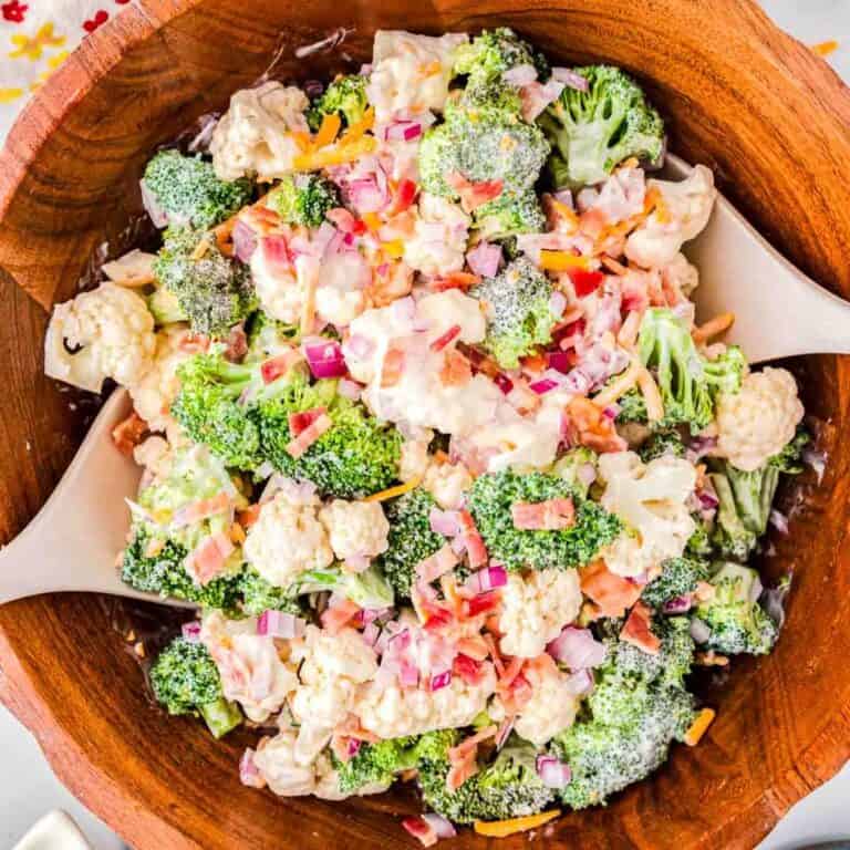 wood bowl filled with broccoli salad with two wood spoons