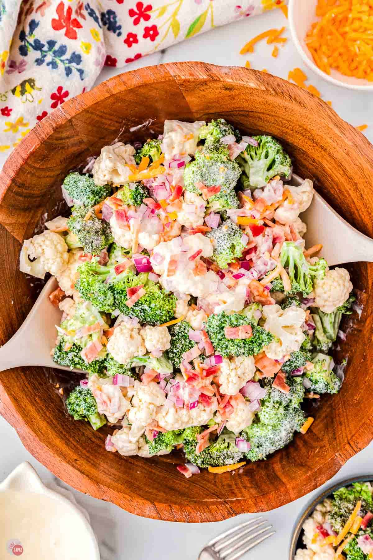 Amish broccoli salad in a wood bowl with two wood spoons
