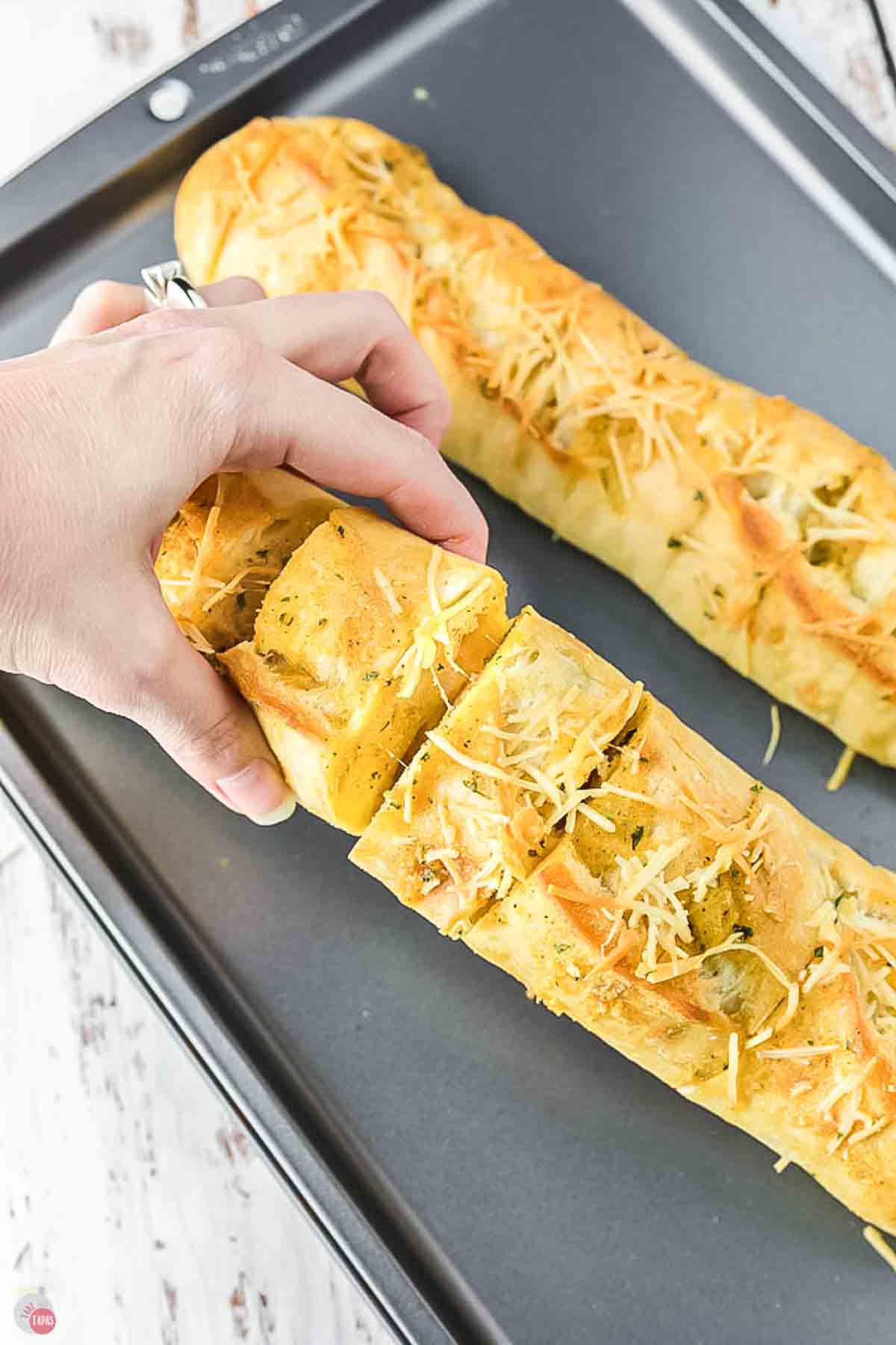 hand grabbing a piece of garlic bread