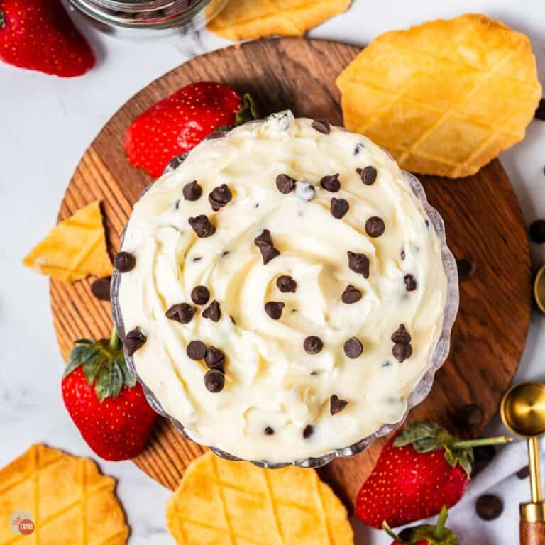 overhead picture of cannoli dip in a clear bowl with strawberries and waffle cone pieces around it
