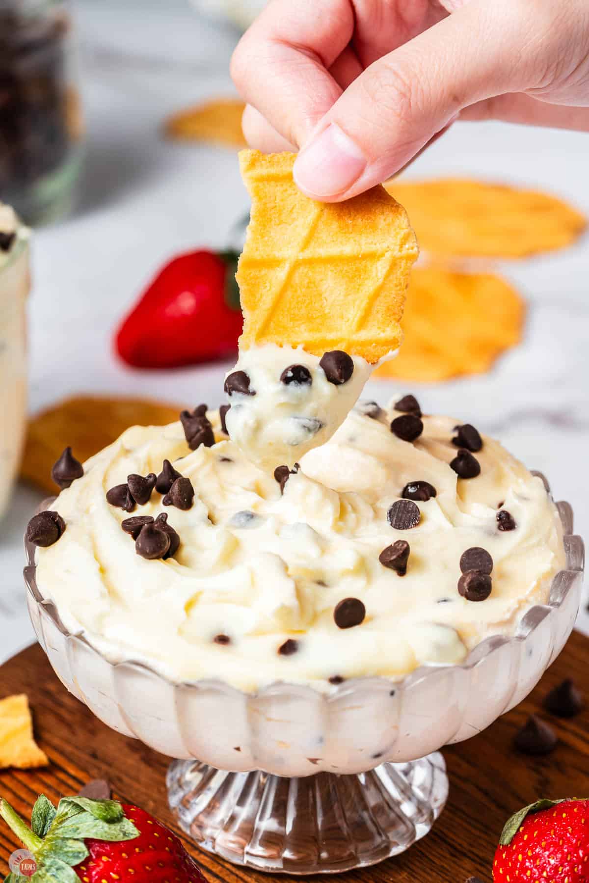 hand dipping a waffle cone pieces in cannoli dip