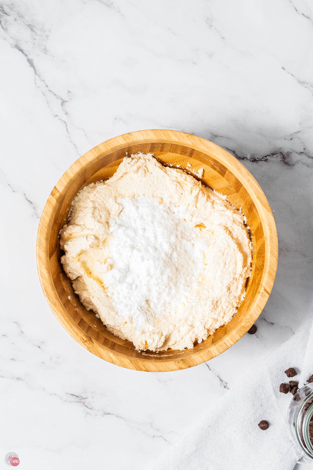 whipped cream cheese with sifted powdered sugar on top in a wood bowl