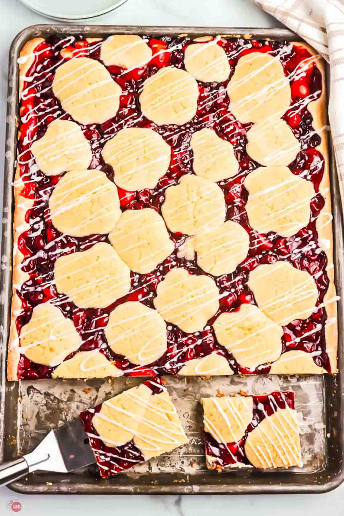 sheet pan with baked cherry pie bars being sliced