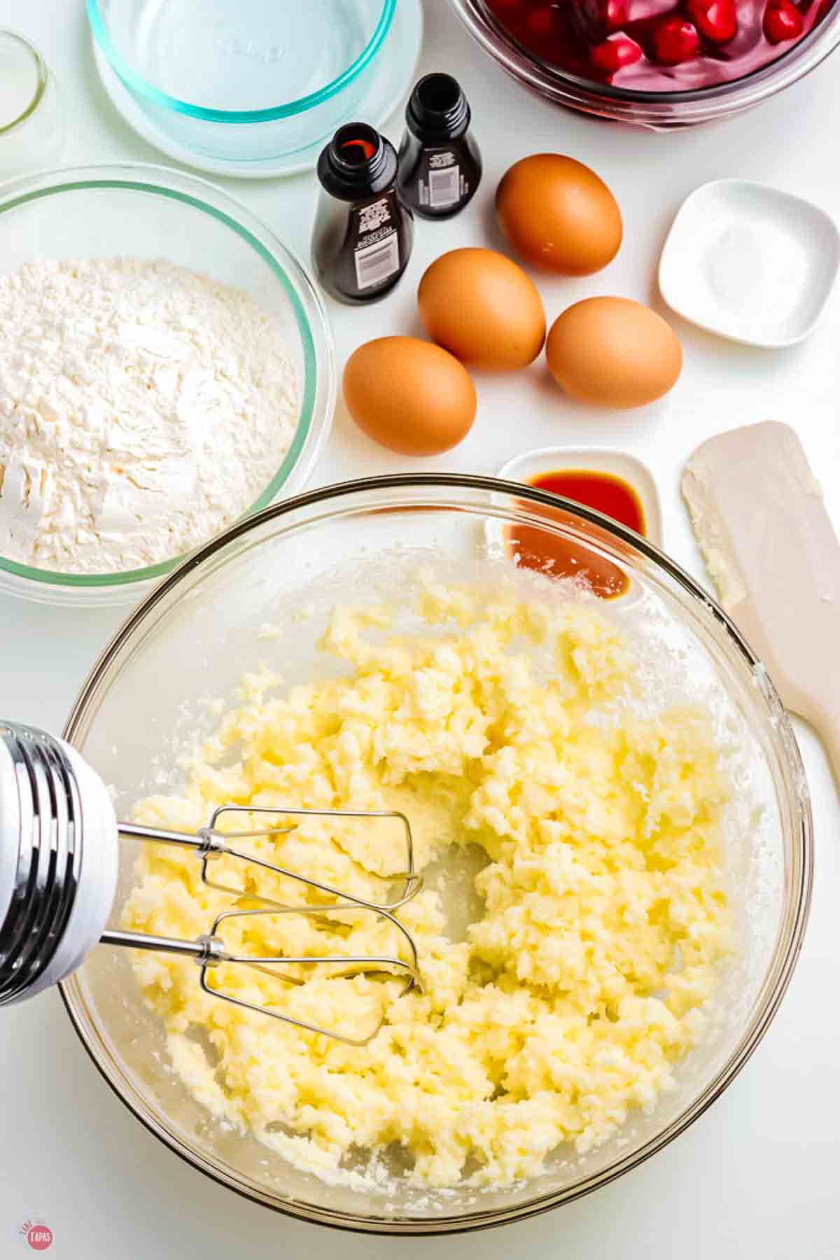 butter and sugar being creamed together with a mixer in a clear bowl