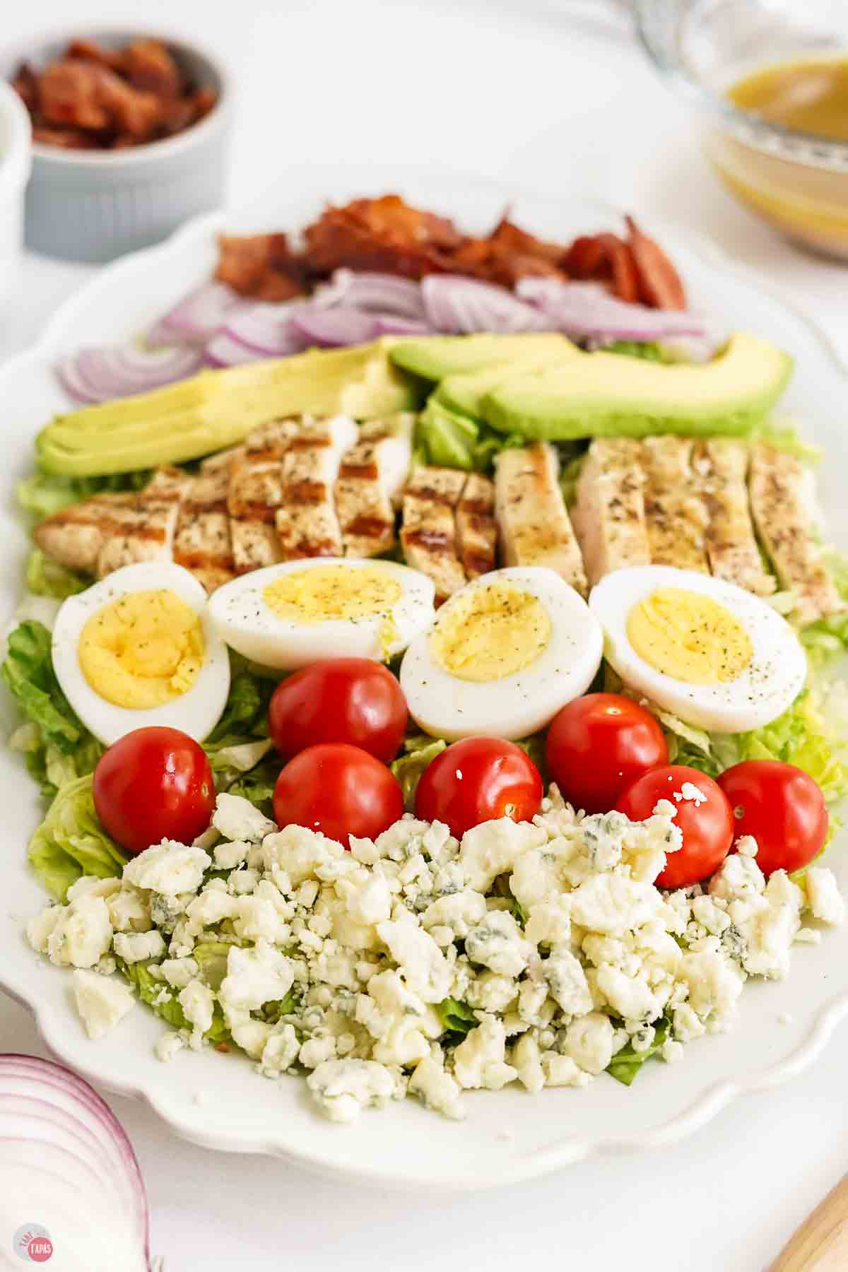 white platter topped with chopped lettuce and groups of toppings assembled on top
