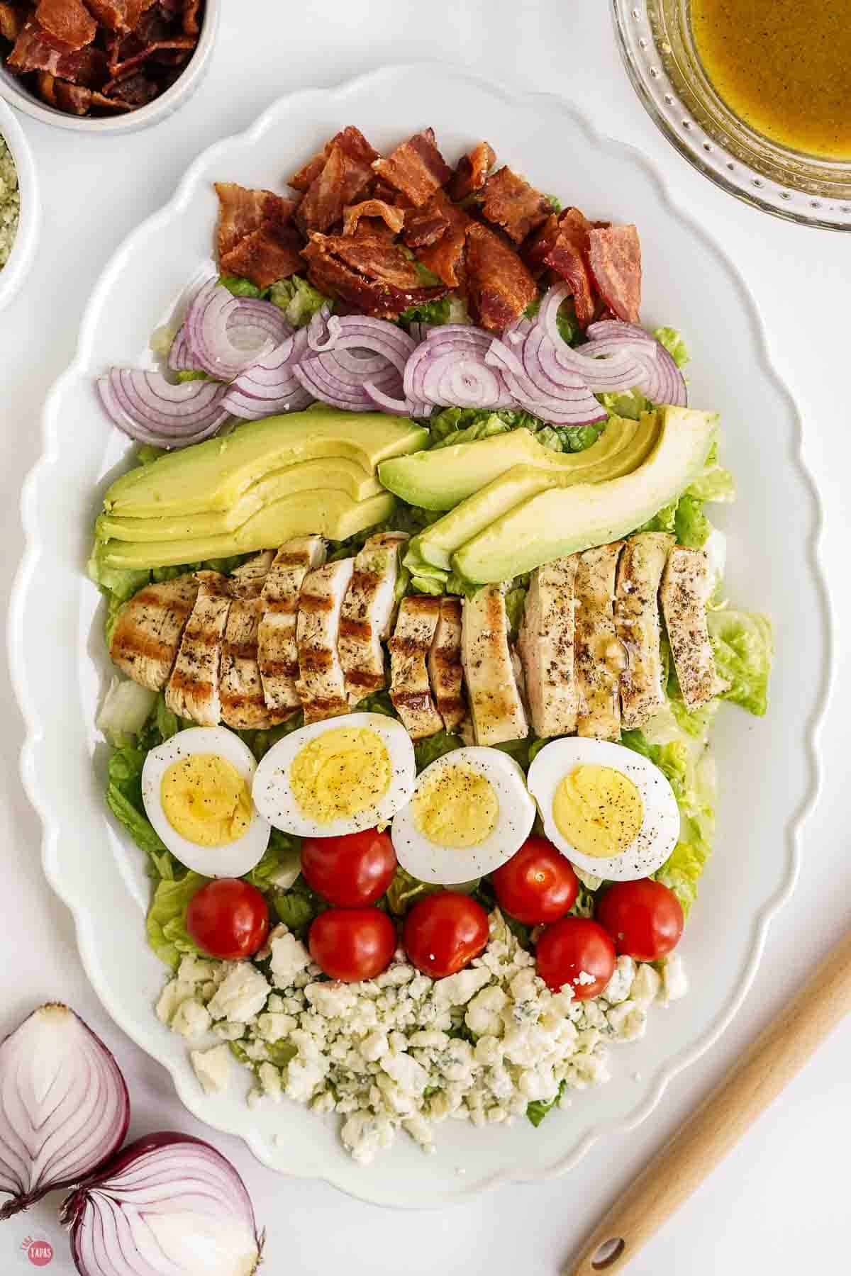 large white oval platter with a cobb salad on it