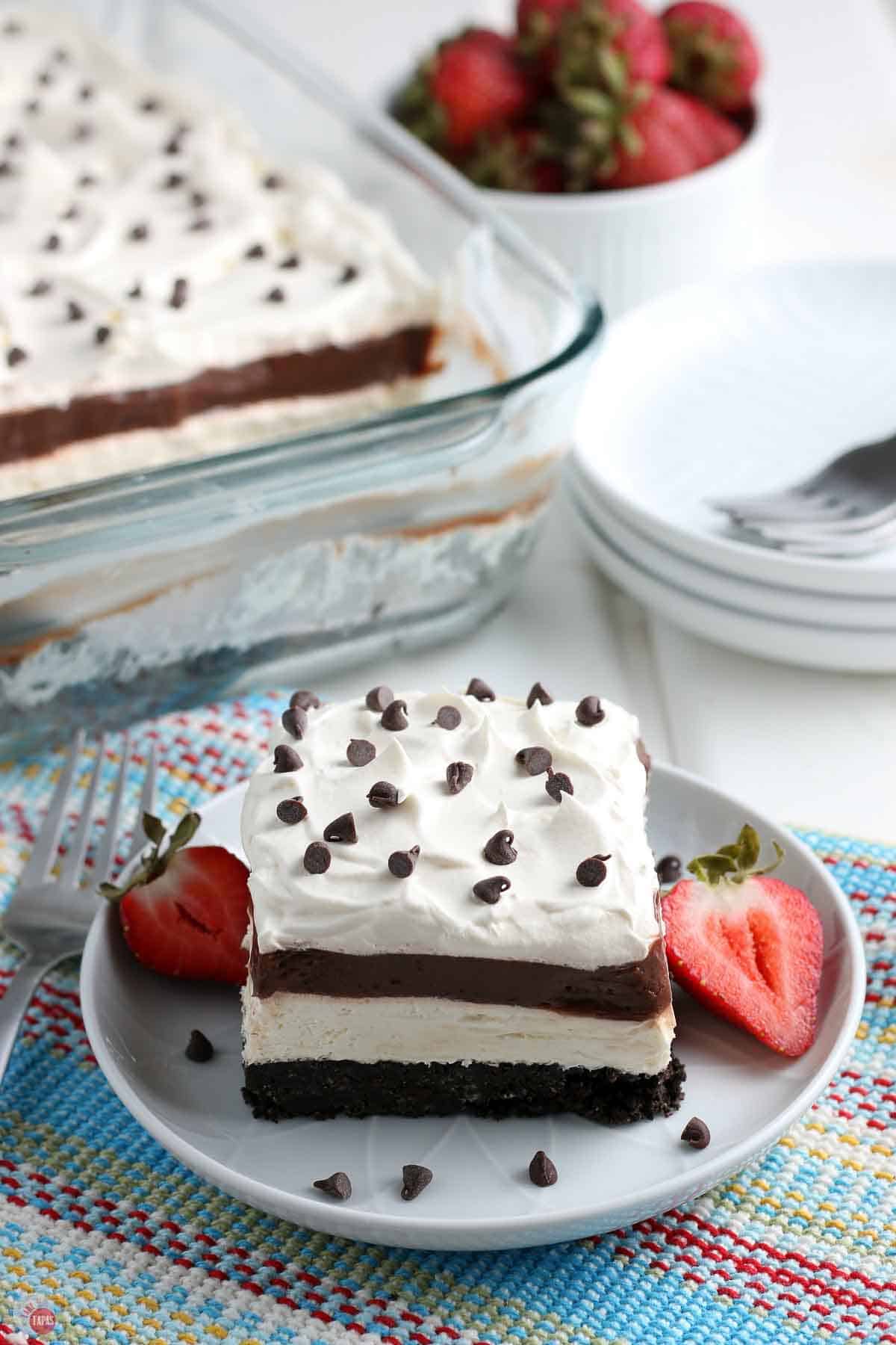 slice of layered dessert on a plate with cut strawberries