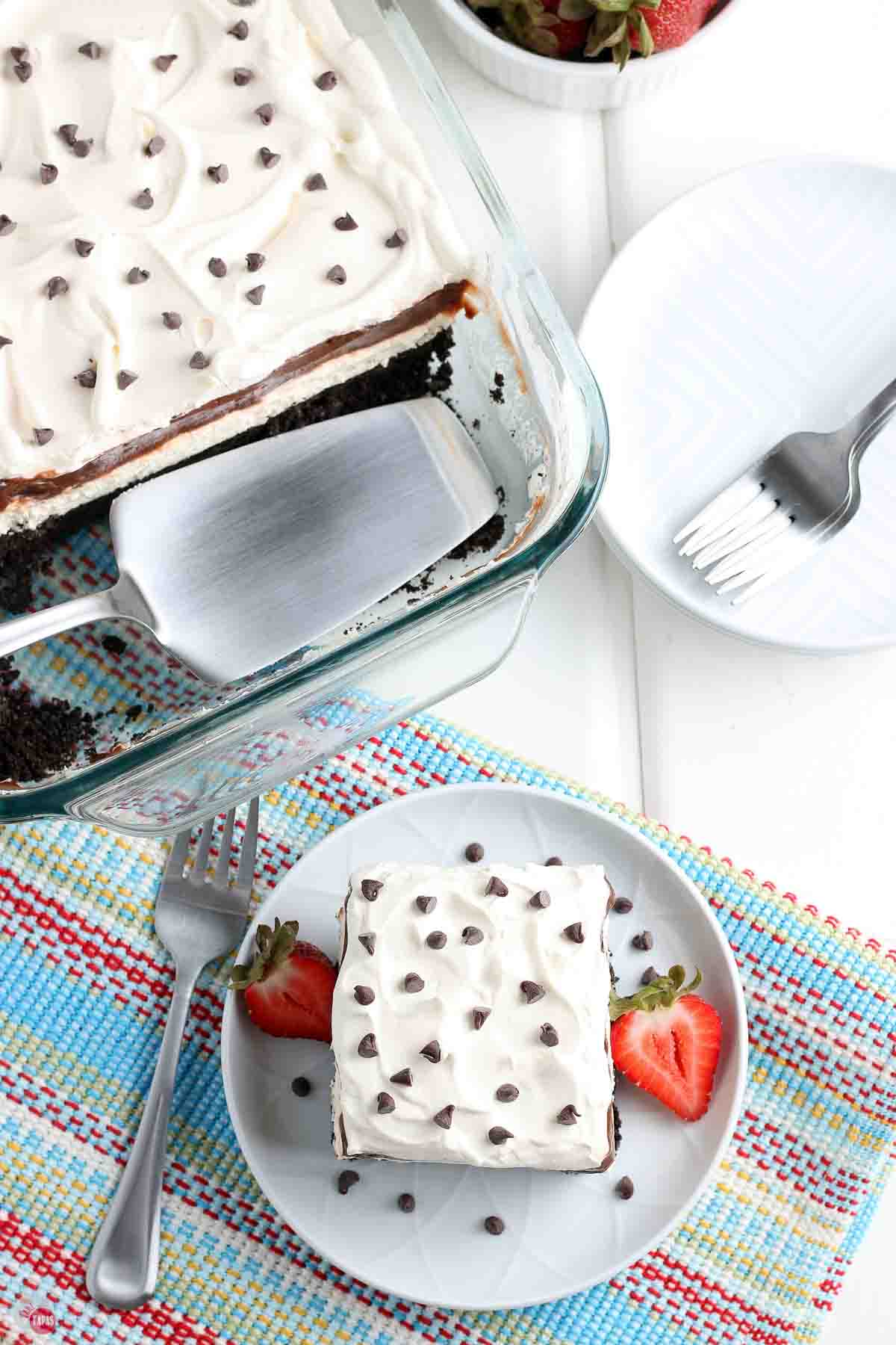 slice of no bake dessert with fruit and a stack of plates and forks