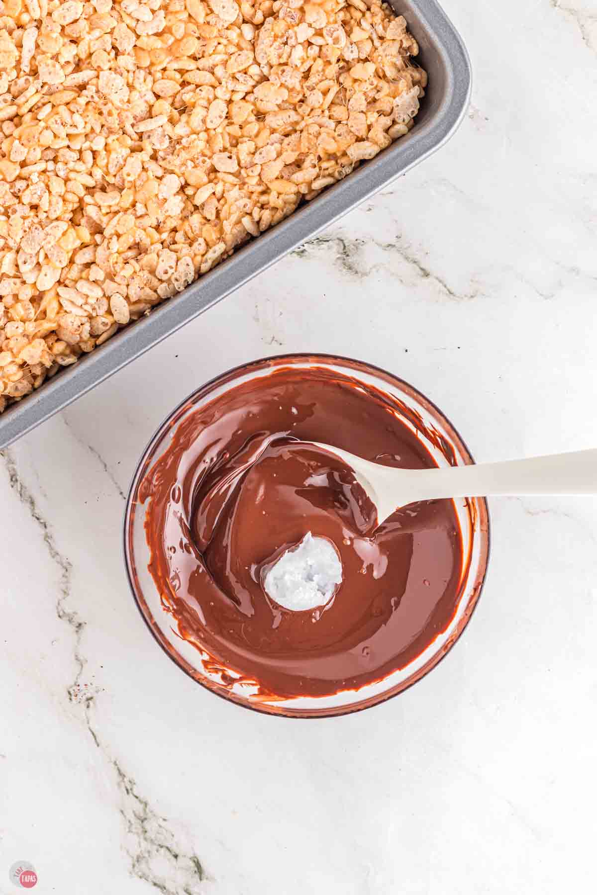 bowl of melted chocolate being stirred with a spoon