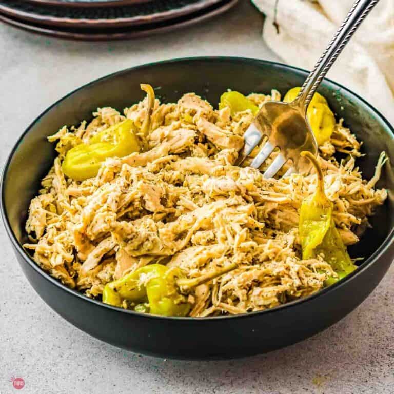 bowl of shredded chicken with a peppers and a fork