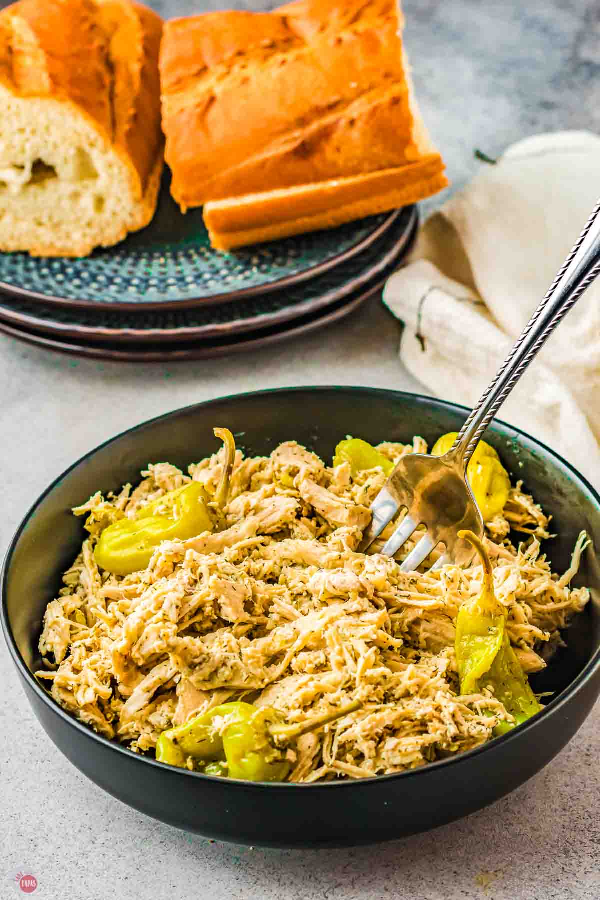 shredded chicken and peppers in a black bowl with a fork