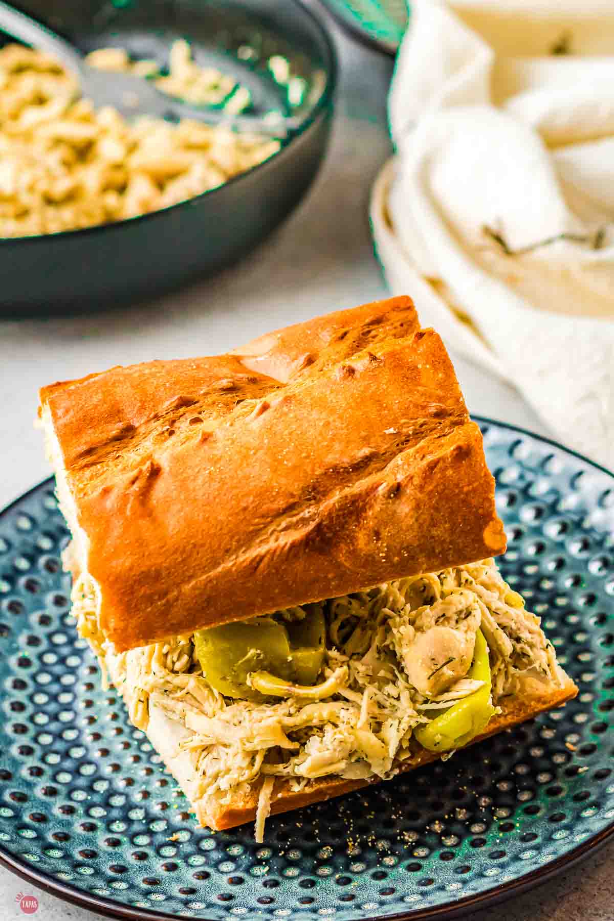 blue plate with sandwich made with shredded chicken and peppers