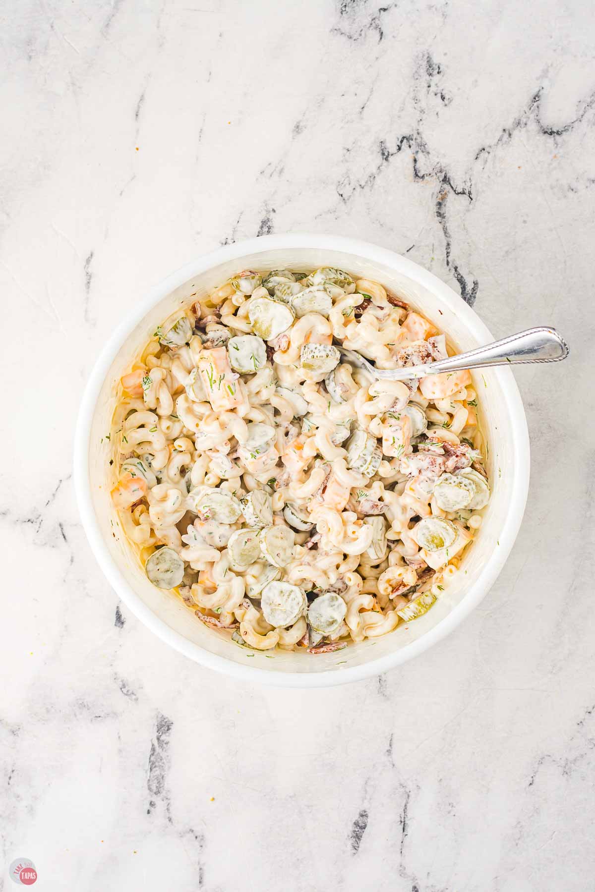 pasta salad being mixed in a white bowl