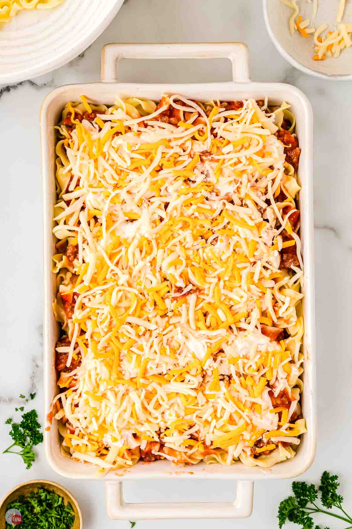 pasta casserole in a dish topped with shredded cheese