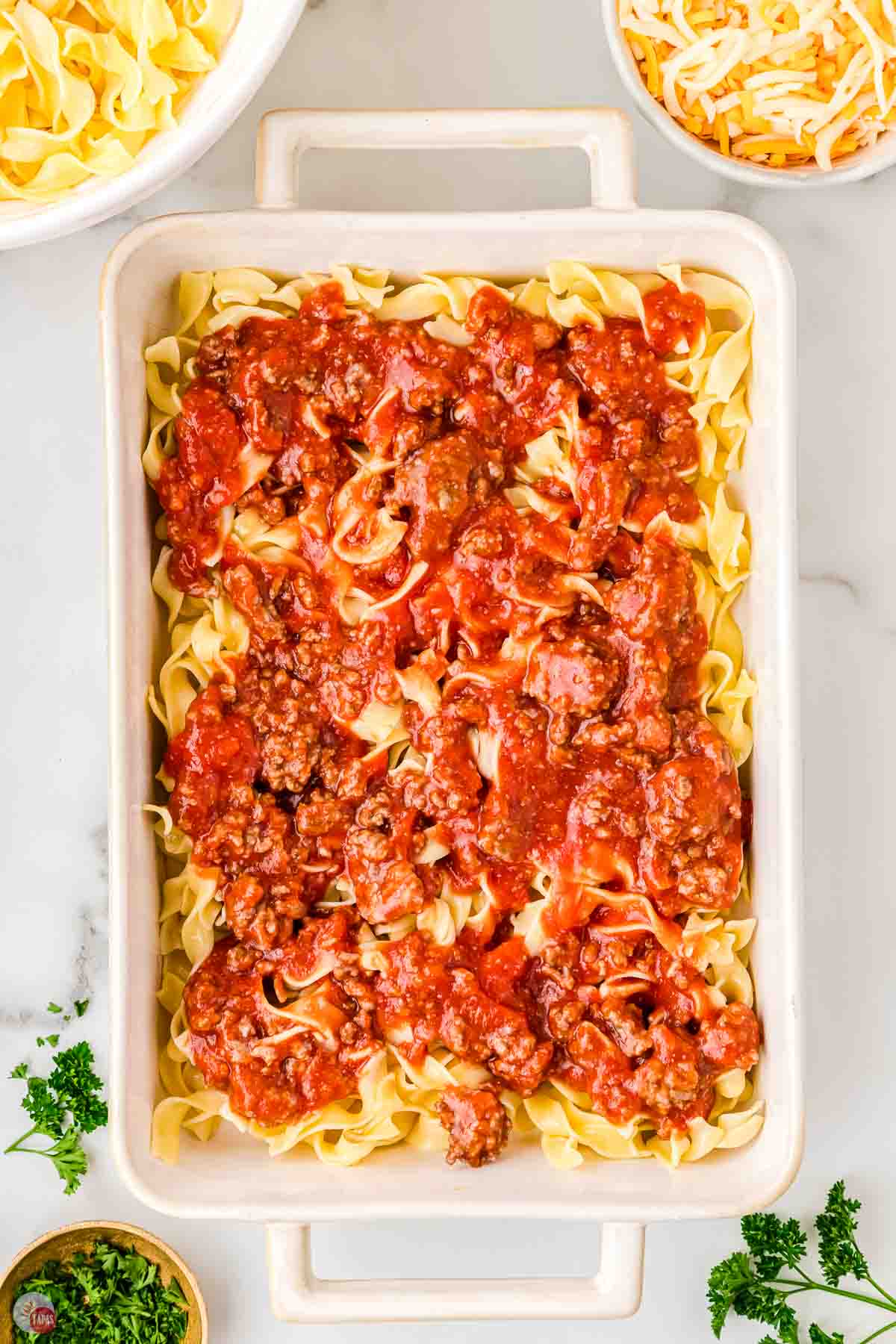 egg noodles in a casserole dish topped with meat sauce
