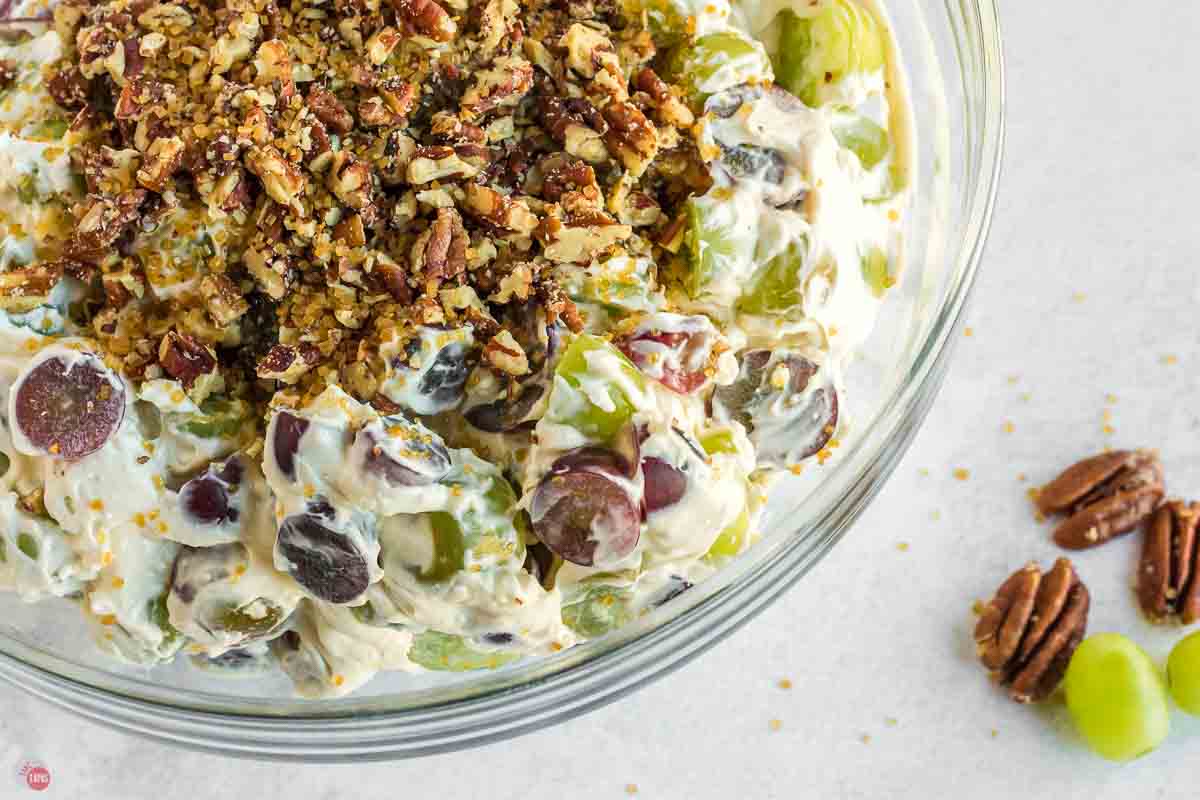 close up of grapes in a creamy dressing in a clear bowl