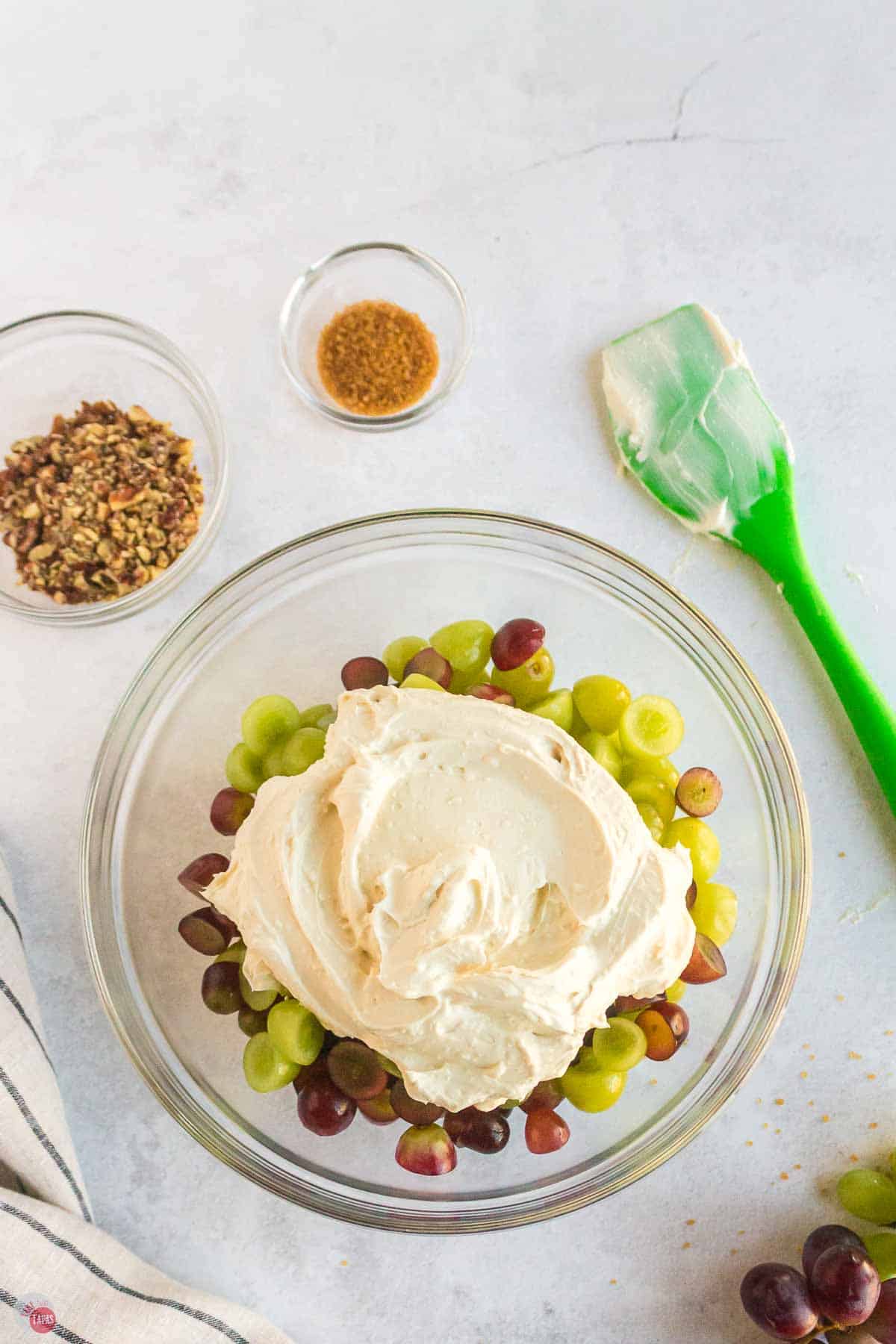 clear bowl of cut grapes topped with whipped cream