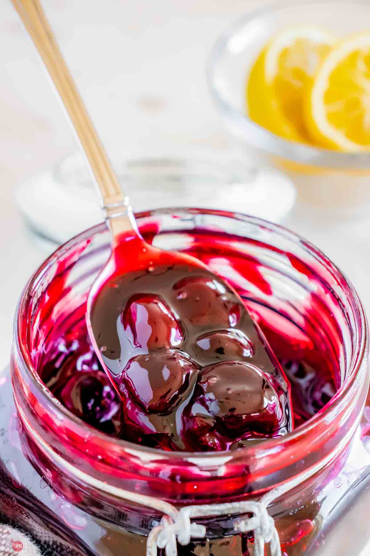 spoon of cherry pie filling being spooned out of a jar