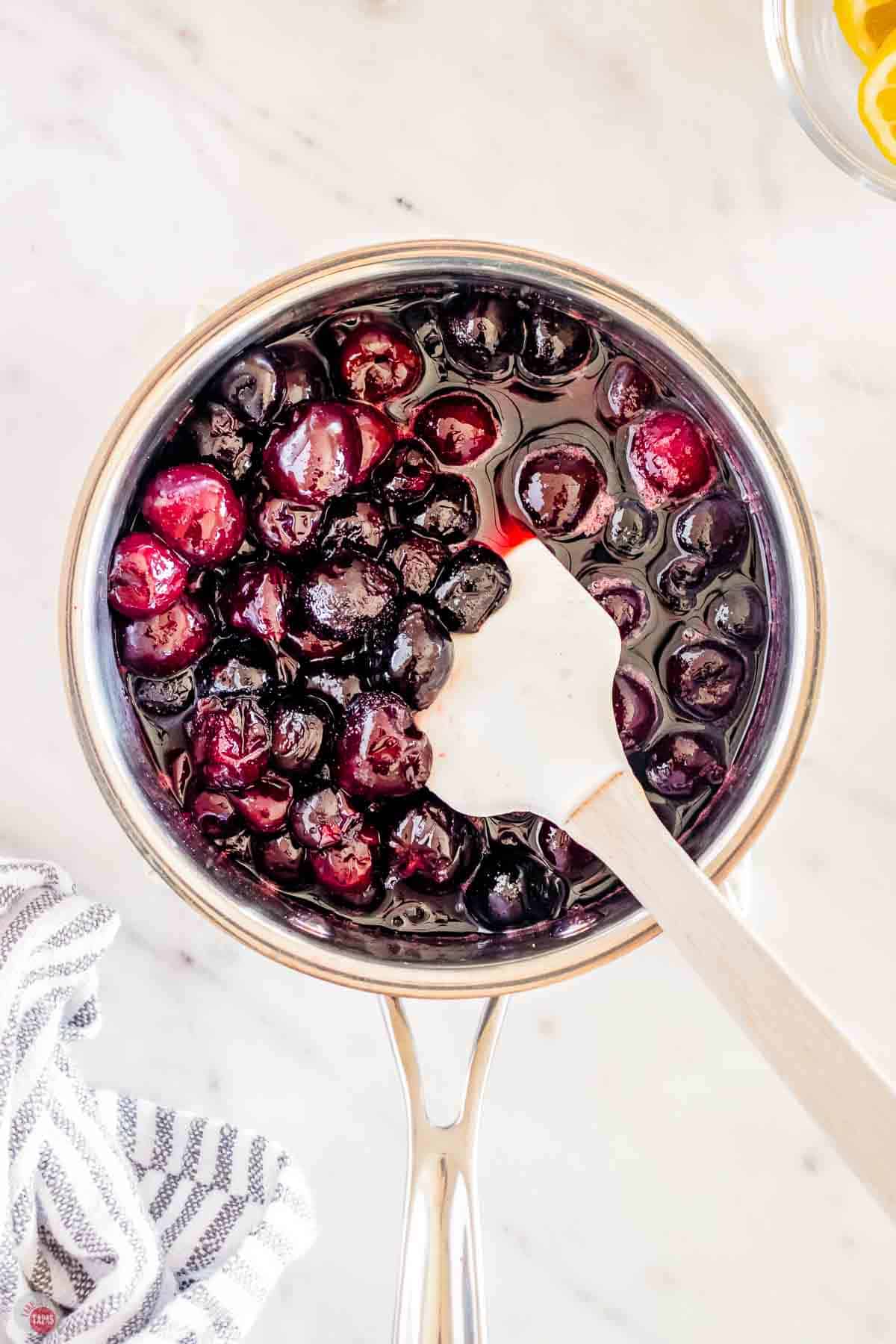 pot of cherries being stirred with a white spatula