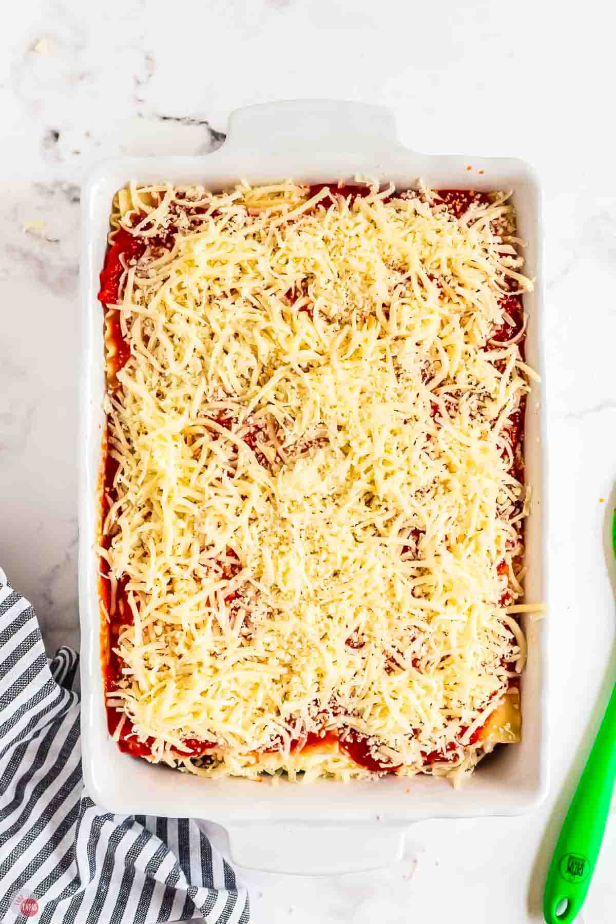 unbaked lasagna topped with shredded cheese