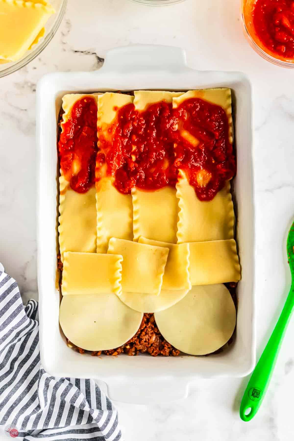 baking dish with layers of cheese, meat, and noodles topped with sauce