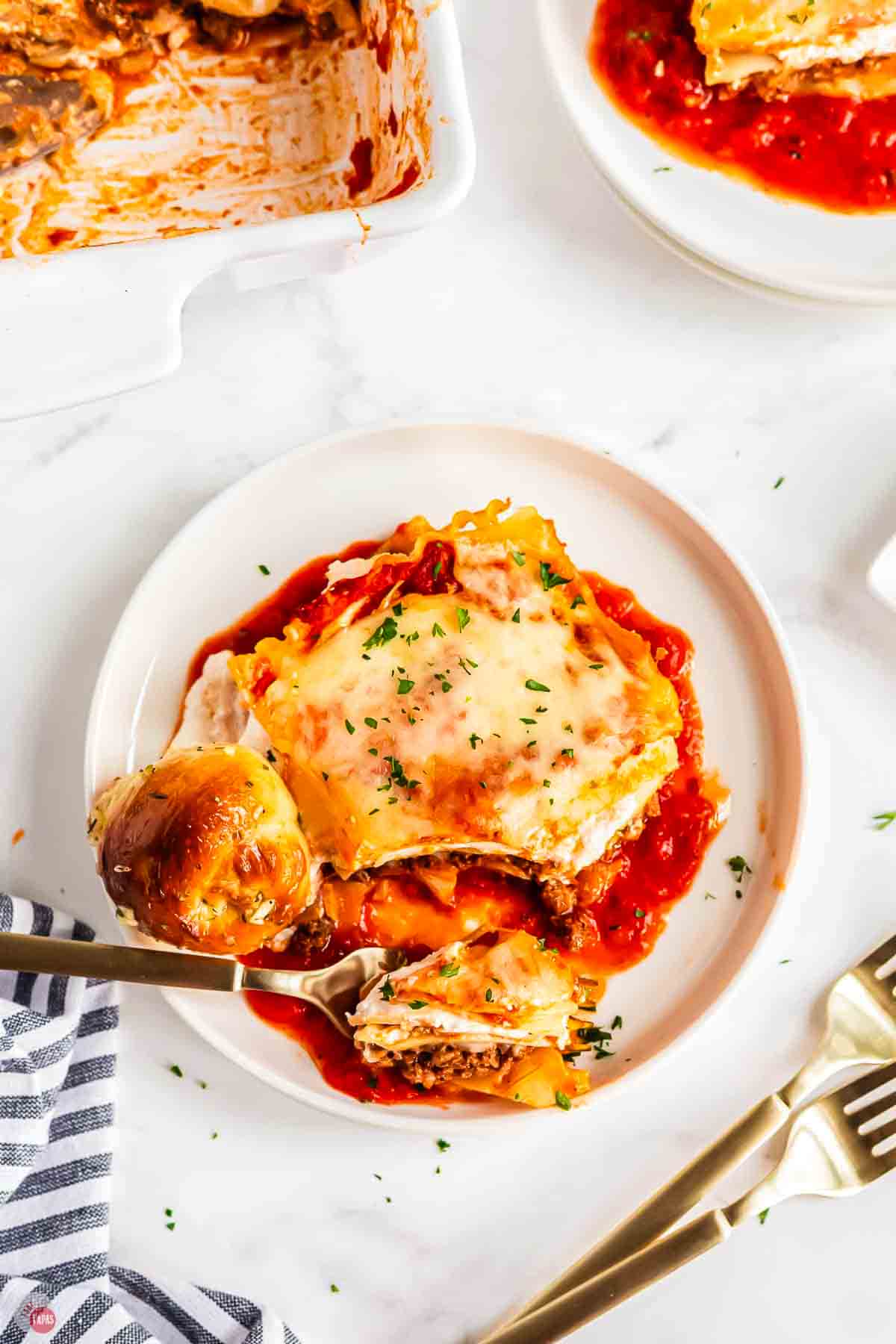plate of lasagna with a fork and roll