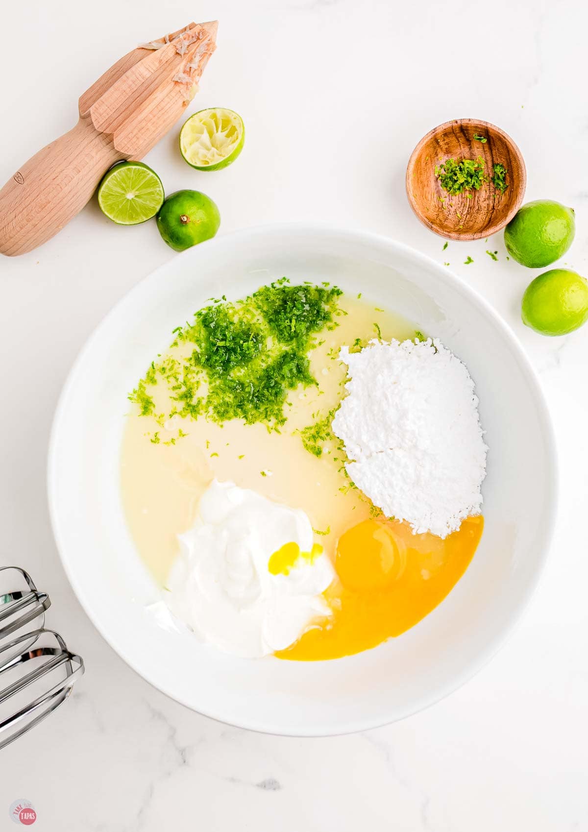 sweetened condensed milk, lime juice, and sour cream in a white mixing bowl