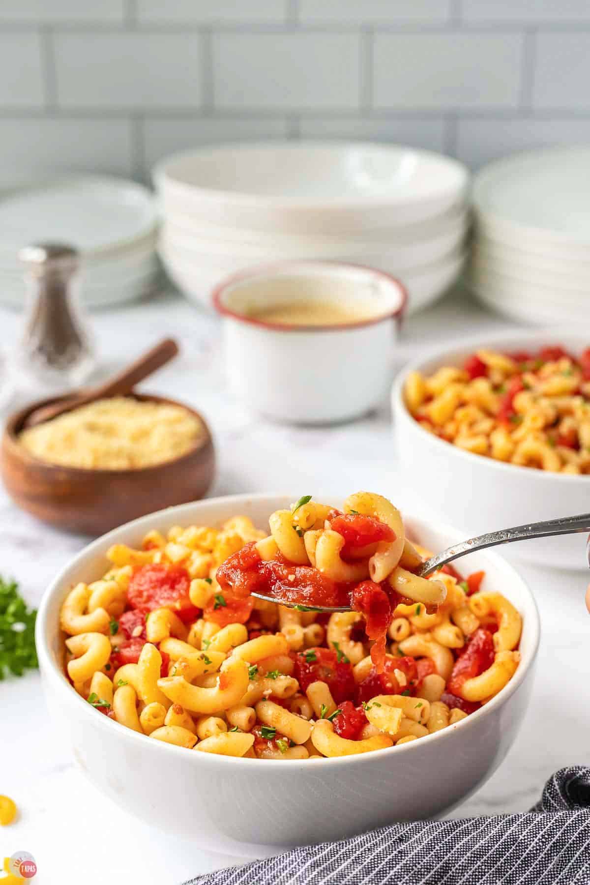 side view of bowls of food and a stack of white plates behind it