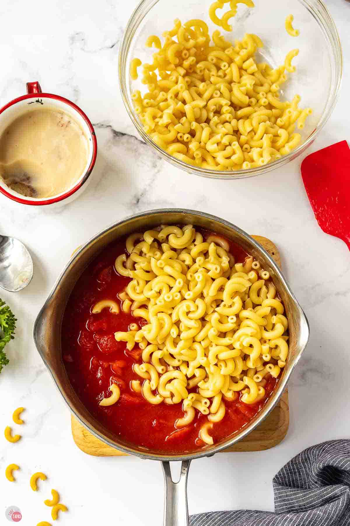 silver pot with tomatoes and cooked elbow macaroni poured on top