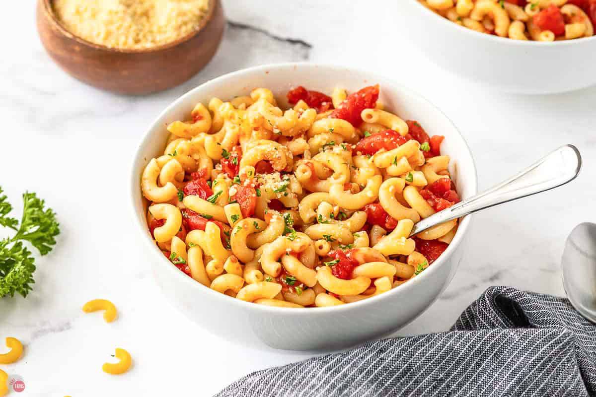 side view of a bowl of macaroni with tomatoes stirred in