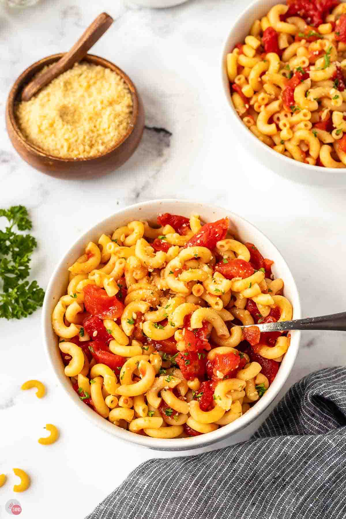 bowl of macaroni noodles and tomatoes with a big spoon