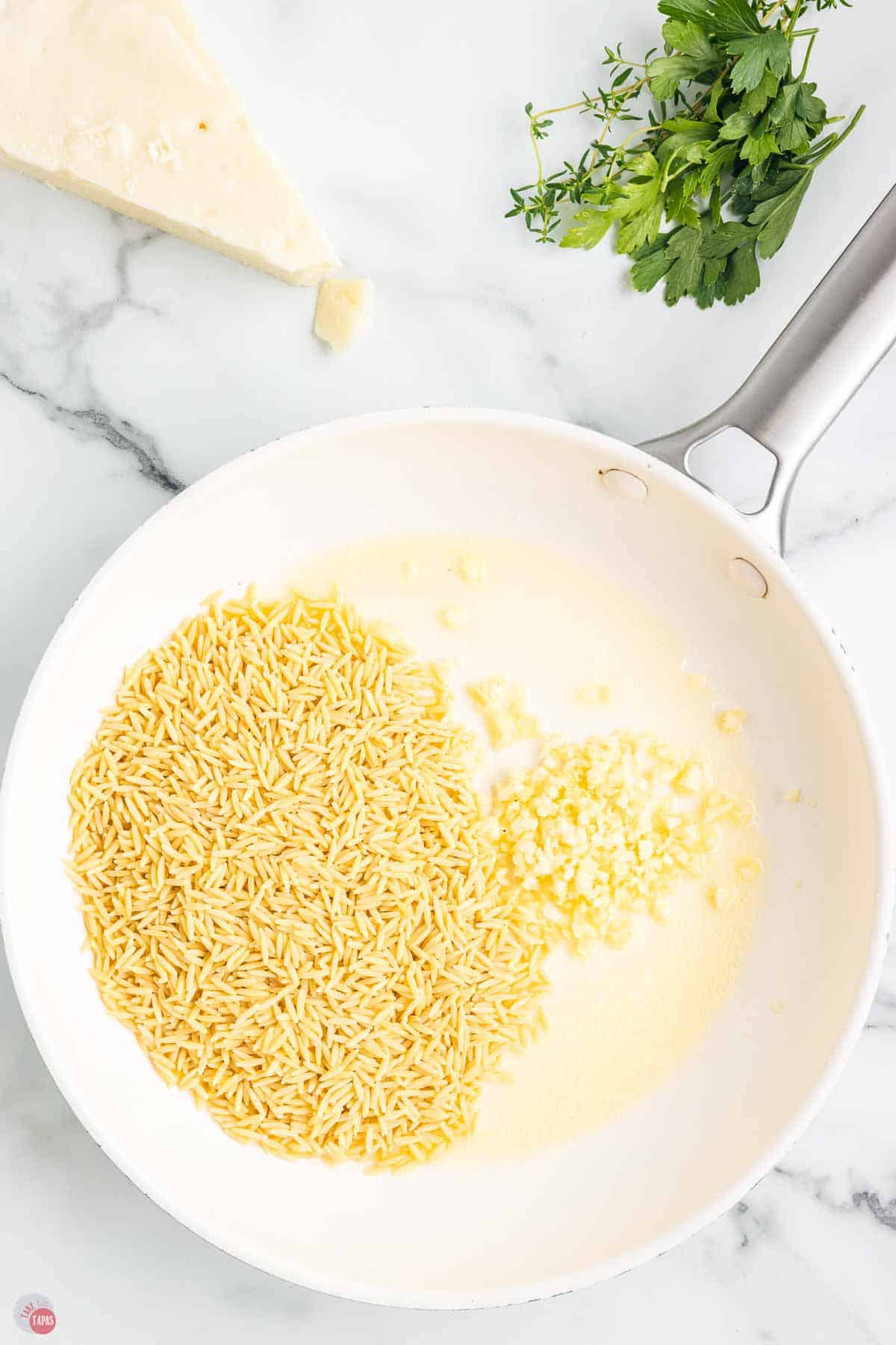 melted butter and orzo pasta in a white skillet